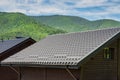 Metal roof construction on a wooden house against a background of mountains. Rain gutter. Royalty Free Stock Photo