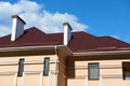 Metal roof and walls of new private house, with chimneys and ventilation on the background of sky, construction concept, family re Royalty Free Stock Photo