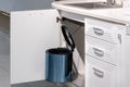 Metal rubbish bin under sink hanging on kitchen cupboard door Royalty Free Stock Photo