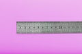 A metal ruler with a scale on a pink background is a superscape with a copy of the space for your text