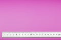 A metal ruler with a scale on a pink background is a superscape with a copy of the space for your text