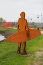 Metal rusty modern monument to surfer on the city riverfront / promenade