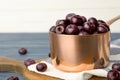 Metal saucepan of fresh acai berries on blue wooden table against white background, closeup Royalty Free Stock Photo