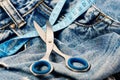 Metal scissors and blue measure tape on jeans. Tailors tools on denim textile, selective focus Royalty Free Stock Photo