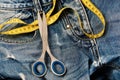 Metal scissors and yellow measure tape on jeans, close up Royalty Free Stock Photo