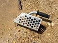 Metal scoop or sieve in sand picking up shells and rocks Royalty Free Stock Photo