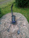 Metal scorpion is sitting on a stone