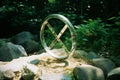 a metal sculpture of a cross on a rock in the woods