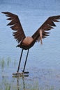 A metal artwork of a Great Blue Heron at the edge of the water