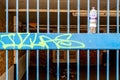 Metal Security Gate Or Fence with Graffiti And A Discarded Plastic Bottle Of Drinking Water