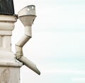 Metal sewer attached to corner of white building.