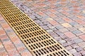 metal sewer grate for drainage system on wet cobblestone sidewalk Royalty Free Stock Photo