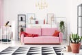 Metal shelves and abstract paintings behind powder pink couch in elegant white living room