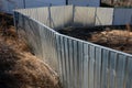 Metal shiny galvanized portable fences delimit the construction site. people are curiously estimating how the construction work is Royalty Free Stock Photo