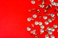 Metal shiny sharp pins or thumbtracks scattered on red background with clean area of photo for labels or headers. Symbol of sympto