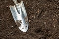 A metal shiny small garden shovel is on freshly plowed ground. Horizontal orientation. Space for text.