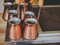 Metal shiny Turks stand on an oven with a sand for making oriental coffee