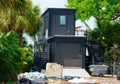 Metal shipping container house under construction on piece of land with lush green trees