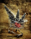 A metal shopping cart  with small decorative Christmas trees on an old weathered wooden surface Royalty Free Stock Photo