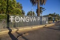 A metal sign on a fence in a gorgeous landscape at Tongva Park with autumn colored trees, lush palm green trees, plants, benches Royalty Free Stock Photo