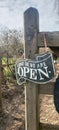 Metal sign on outside wooden post stating we are open.