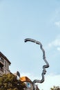 Metal sign resembling a human face from a side on a backdrop of a blue sky