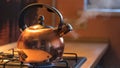 A metal silver teapot on a gas stove in the kitchen at home. Concept. Close up of steel kettle with boiling water Royalty Free Stock Photo