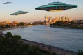 A metal and silver UFO invasion of planet Earth, a group of spaceships fly in the sky above the city and emit yellow rays to the Royalty Free Stock Photo