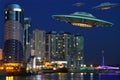 A metal and silver UFO invasion of planet Earth, a group of spaceships fly in the sky above the city and emit yellow rays to the Royalty Free Stock Photo