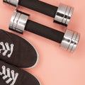 Metal small dumbbells and sneakers for training on a pink background. Royalty Free Stock Photo
