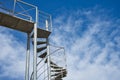 Metal spiral staircase on a blue sky background Royalty Free Stock Photo