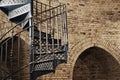 Metal spiral staircase span in retro style on the background of an old stone wall with arches Royalty Free Stock Photo