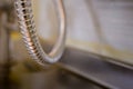 Metal spiral hose on textured stainless steel surface of kitchen worktop.