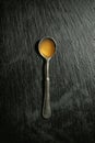 Metal spoon with aromatic honey on dark background