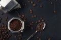 Metal spoon with coffee beans and coffee maker on dark textured background. Top view. Copy space Royalty Free Stock Photo