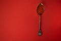 Metal spoon with elegant handle on bright red background. Red caviar of salmon species of fish in the spoon