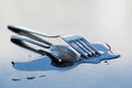 Metal spoon and fork on a large water drop on a clean surface Royalty Free Stock Photo