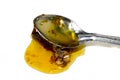 Metal spoon with a pouring drop of golden honey Royalty Free Stock Photo