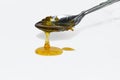 Metal spoon with a pouring drop of golden honey Royalty Free Stock Photo