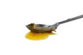 Metal spoon with a pouring drop of golden honey Royalty Free Stock Photo