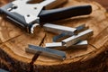 Metal stapler and steel staples on stump, macro