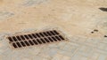 Metal storm drain with holes for water drainage in the road paved with paving slabs in the city Royalty Free Stock Photo