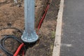 Metal support construction positioned right above narrow shallow trench dug in ground with thick red cable inside
