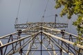 Metal support of high voltage power lines against a dark sky and green vegetation. The concept of power, transport of electrical Royalty Free Stock Photo