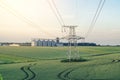 Metal support is a pillar of a high-voltage line in the field. Big elevator on the background. Industrialization of agriculture Royalty Free Stock Photo