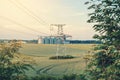 Metal support is a pillar of a high-voltage line in the field. Big elevator on the background. Industrialization of agriculture