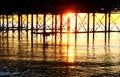 The metal support strutts of Brighton Pier glowing yellow with the sun setting underneath it