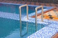 A metal swimming pool safe ladder (skimmer) on the entrance to the home inground poolside