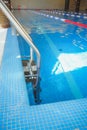 Metal swimming pool steps.Interior of sport hall.Stainless steel swimming pool. hand rails of swimming pool.Ladder in the still