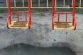 Metal swing with a wooden seat on a kids playground on a rainy day with a puddle under it